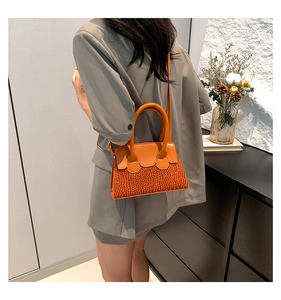 Detailed view of orange textured crossbody bag with crocodile pattern and golden hardware