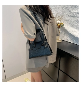 Detail of black crossbody bag featuring textured pebble leather and smooth matte finish