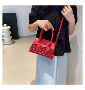 Detail of red crocodile pattern handbag with dual handles and matching shoulder strap