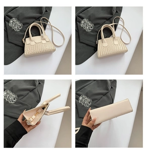 Detail view of cream crocodile embossed handbag with gold hardware and shoulder strap