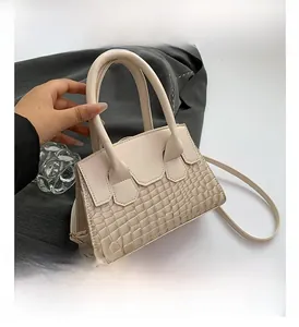 Close-up of beige handbag featuring crocodile pattern embossing and smooth faux leather finish