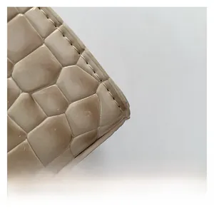Detailed close-up of cream crocodile pattern texture and precision stitching on the handbag