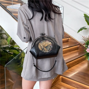 Retro black shell bag with elephant embroidery and chain strap on a model