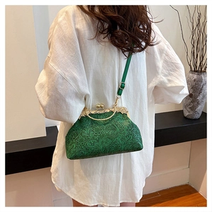 Macro view of green retro embossed leather shell bag with gold clasp and chain strap
