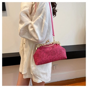 Detail of rose red embossed shell bag with gold clasp and leather shoulder strap
