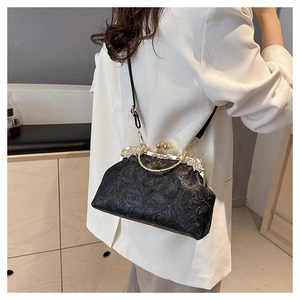 Detail of black shell-shaped bag with floral embossing and gold metal handle
