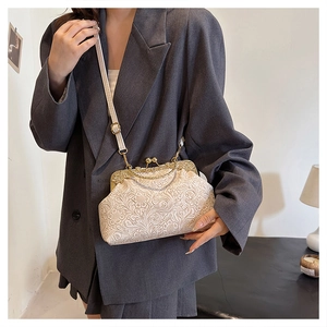 Detail of vintage cream shell bag with embossed floral texture and gold metal clasp