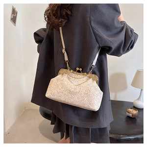 Detailed macro of vintage beige shell bag with floral embossing and gold metal clasp