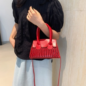 Red crocodile texture crossbody handbag with dual handles and elegant trapezoid shape
