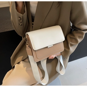 Detail of minimalist two-tone crossbody bag with wide strap and premium stitching