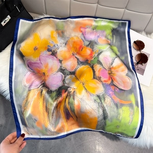Close-up of oil painting style floral silk scarf on white plush rug with accessories