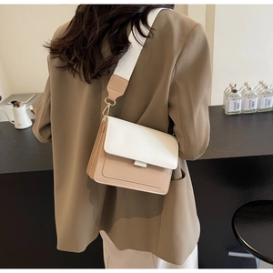 Crossbody bag with wide fabric strap shown on model in a modern cafe setting