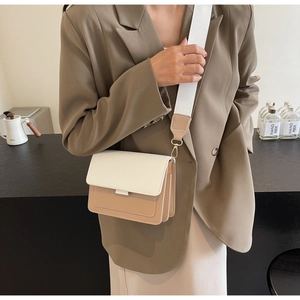 Detail of minimalist cream and khaki crossbody bag with wide shoulder strap worn by model