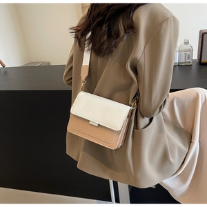 Detail of contrast flap crossbody bag with wide strap and gold hardware on model