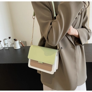 Detail of a chic three-color crossbody bag with a gold chain strap on a brown blazer