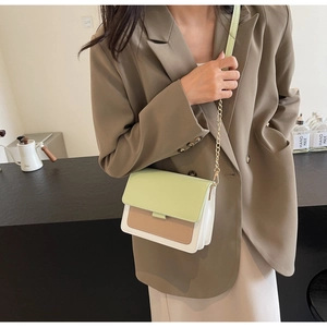 Detail view of a color-block flap crossbody bag with mint green and beige paneling