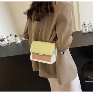 Detail of color-block flap crossbody bag with gold chain strap on a model
