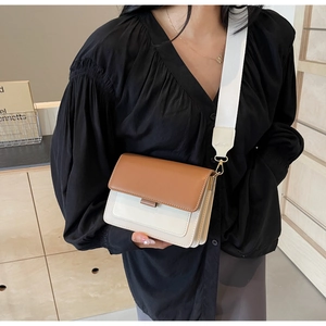 Detail of trendy color-block crossbody bag featuring wide fabric strap and gold buckles