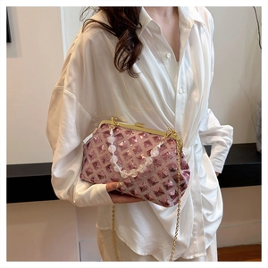 Detail of pink sequin clutch bag with bead handle and gold chain strap on a model