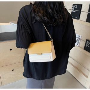 Detailed back view of a yellow and white crossbody bag with golden chain strap
