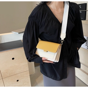 Close-up of stylish contrast color crossbody bag with adjustable wide strap on model