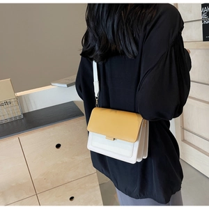 Rear view of model wearing the yellow and white crossbody bag in a stylish home setting