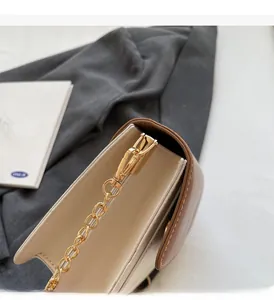 Detail of contrast stitch and premium gold chain on cream and brown crossbody bag