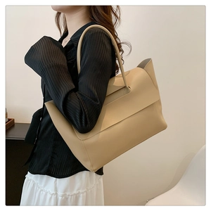 Detailansicht der beigefarbenen Ledershopper mit perforiertem Griff und minimalistischer Klappe