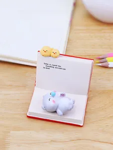 Detail of cute animal resin figures on a miniature red book desk decor and phone stand