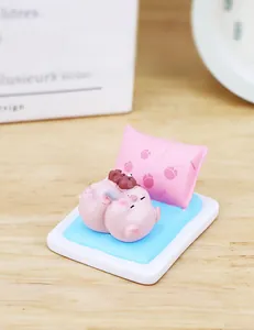 Cute pink pig figurine lying on blue mattress holding a brown bear cub tabletop decor
