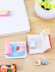Detailed view of miniature sleeping pig and reading cat figurines on a wooden desk