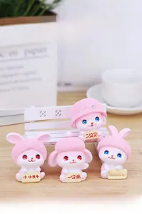 Close-up of four pink resin bunny figurines with hats and sweet message signs on a desk