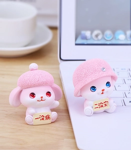 Detail of pink resin bunny figurines with health and peace wishes on a desk