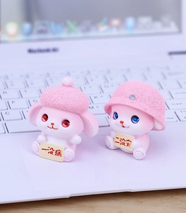 Detail of cute pink resin bunny figurines holding yellow blessing charms for desk decor