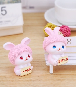 Detail of pink resin bunny figurines with matte hats and cute mini message signs
