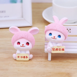 Cute pink resin rabbit figurines set with decorative signs on a cozy wooden desk