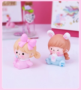 Close-up of two cute resin girl figurines with pink and blue outfits for car desk decor