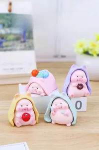 Macro shot of cute resin pig figurines with colorful cloaks on a cozy wooden desk