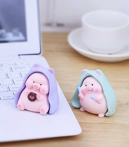 Close-up of cute resin pig figurines with colorful blankets on an office desk