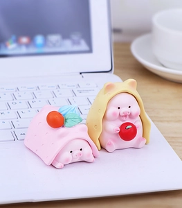 Detail of two resin pig figurines with dotted hoods on a white laptop keyboard