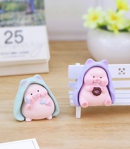 Close-up of cute resin pig figurines with colorful hoodies and miniature dining props