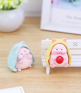Detail of cute resin pig figurines featuring a pink piglet with a blue polka dot cape