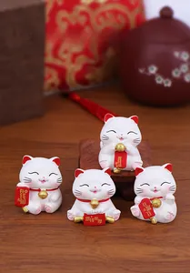 Set of four mini resin fortune cats with lucky charms on a dark wood surface
