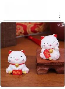 Detail of two mini ceramic fortune cats with lucky scrolls on a wooden base