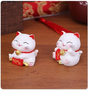 Miniature resin Fortune Cat figurines with lucky scrolls on a traditional wooden desk