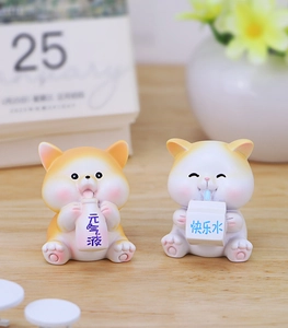 Close-up of resin cat figurines holding milk bottles on a cozy wooden desk setup