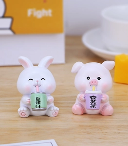 Close-up of cute resin rabbit and pig desk figurines with cartoon drink accessories