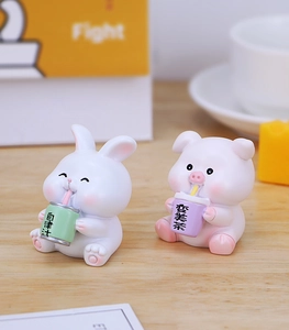Macro shot of cute resin rabbit and pig miniatures with tea cups on a wooden desk