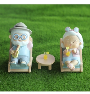 Detailed resin figurines of elderly couple on lounge chairs with ukulele and drinks