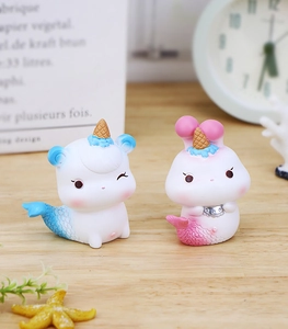 Détail de figurines d'animaux sirènes en résine avec finition mate sur un bureau en bois